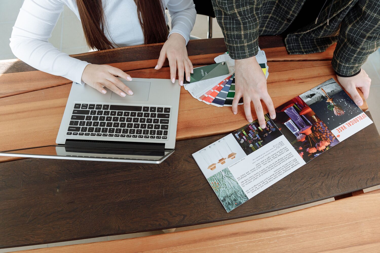Creative team pairing brand colour swatches and printed design work with a laptop — the creative craft CWA Europe adds to digital marketing