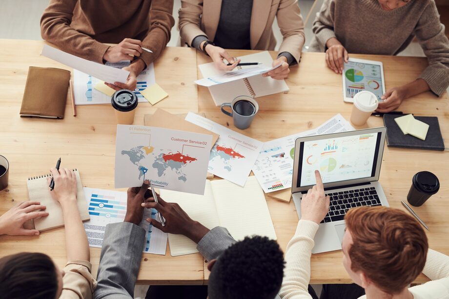Diverse digital marketing team reviewing campaign strategy, analytics charts and an international audience map around a table