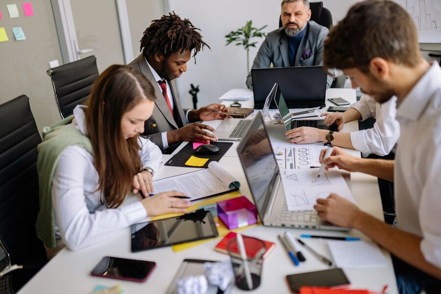 Founder-led digital marketing team collaborating around laptops in the office